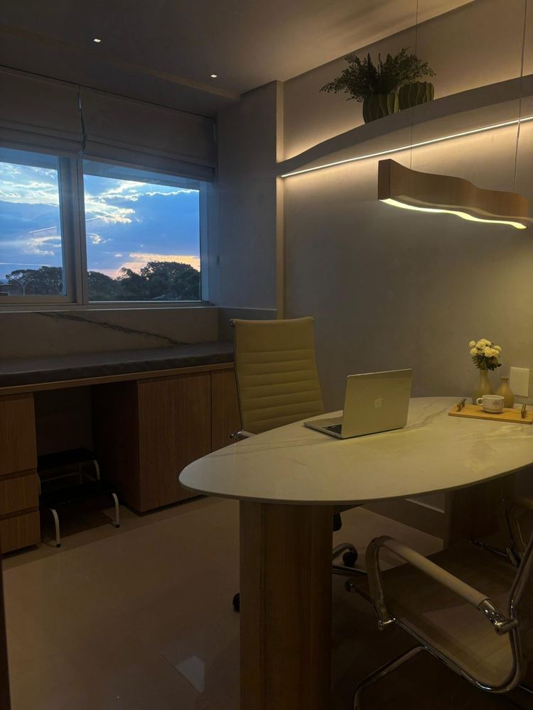 Consultório ao entardecer, com janela e mesa oval